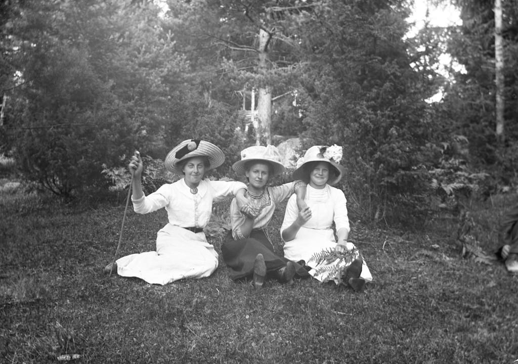 #62 Three happy women sitting on the grass.