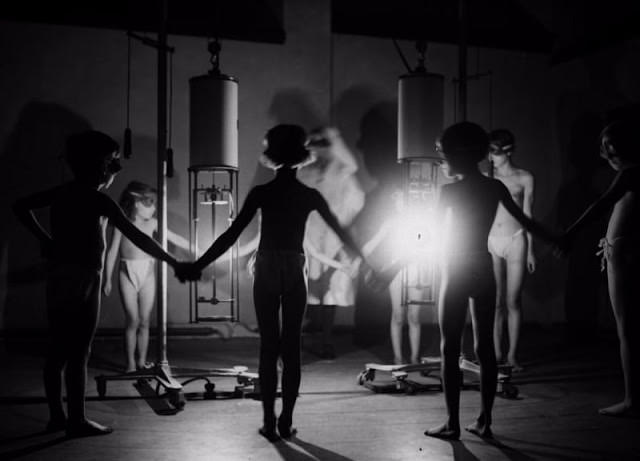 Children around a radiating glow of ultraviolet light at the Institute of Ray Therapy.