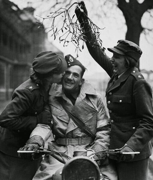 #10 An ATS girl kisses a soldier under some mistletoe held aloft by her friend, while their depot is preparing for Christmas Day. 20th December 1939