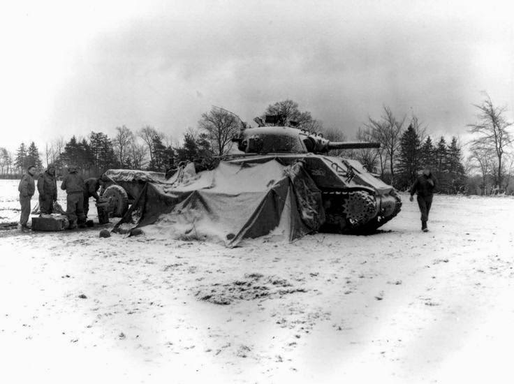 #18 US 5th Armored Regiment tankers gathering around a fire and opening Christmas presents, near Eupen, 30 december 1944; note M4 Sherman tank.
