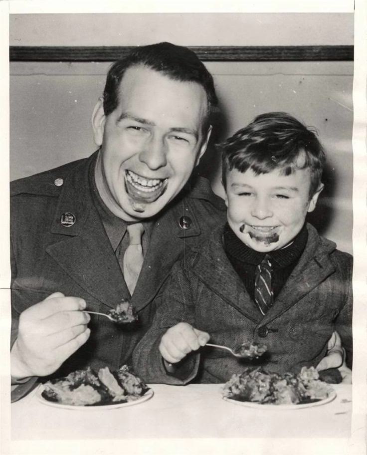 #20 U.S. soldier eating ice cream with a little British boy at Christmas party given by troops of the USAAF Service Command for 100 English evacuees at a station “somewhere” in England, 1943.