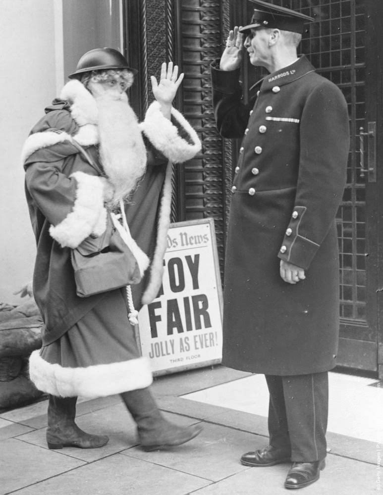 #23 Even Father Christmas follows the war time safety precautions as he arrives this year, complete with tin helmet and gas mask case, at London’s famous Brompton road store, Harrods. 6th November 1939.