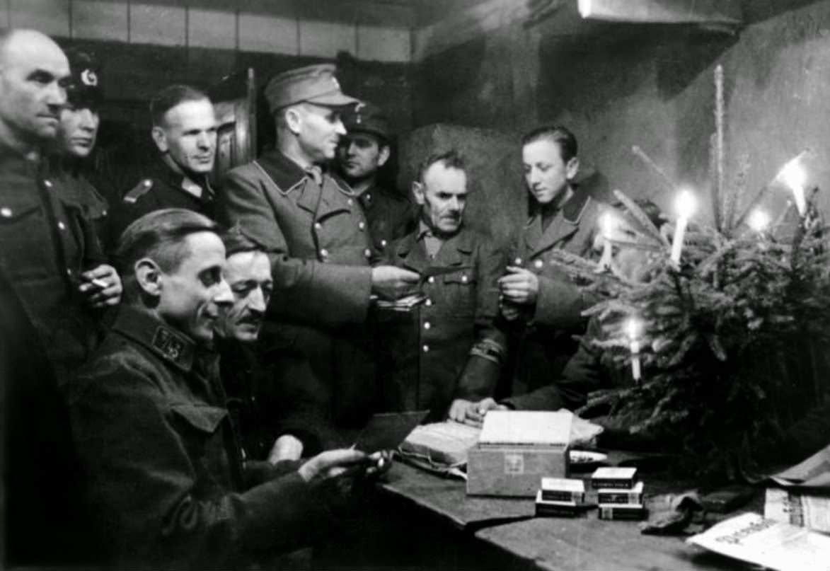 #28 German soldiers of the Volkssturm celebrate Christmas in a cellar, sharing with each other cigarettes and holiday messages from home delivered on postcards. The Volkssturm was established on 18 October 1944.