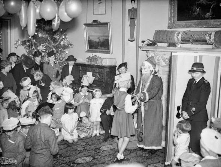 #3 A Christmas party held at Admiralty House, London, 17 December 1942 for allied naval officers children. ‘Father Christmas’ in a costume and mask presents a young girl with a gift.