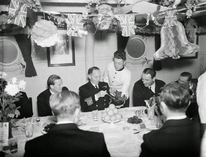 #41 The Captain of HMS MALAYA helping himself to plum pudding during Christmas dinner at Scapa Flow, 25 December 1942.