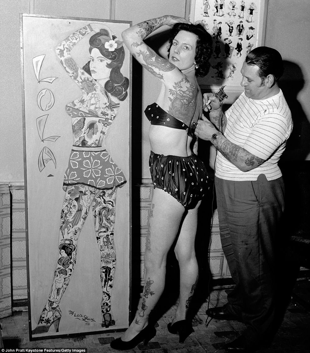 #13 Tattooist Les Skuse at work on tattooed beauty Pam Nash, ca. 1960s.