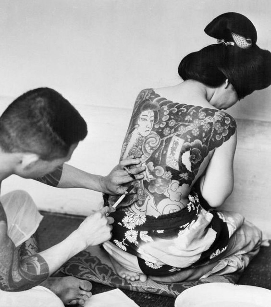 #48 A woman lays her Kimono down as she gets a traditional Japanese tattoo, ca. 1930s.