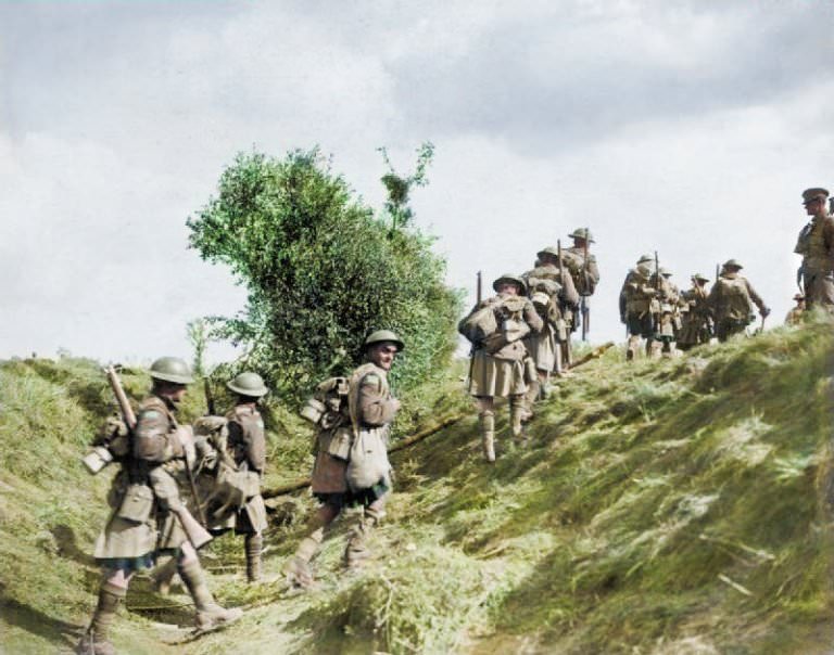 #17 Scottish troops march with combat gear and rifles slung over their backs as they make their way over a grassy mound during the Battle of the Canal du Nord, 1918.