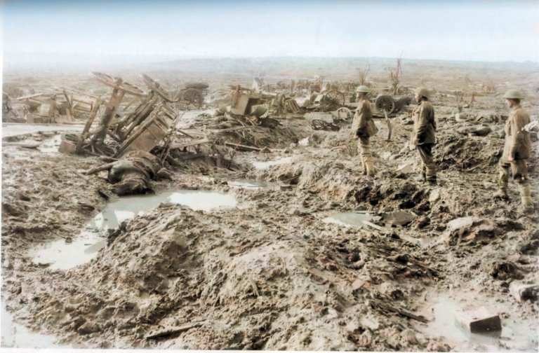 #5 Three soldiers look out across a battlefield where wagons are upturned and destroyed and craters break up the mud.