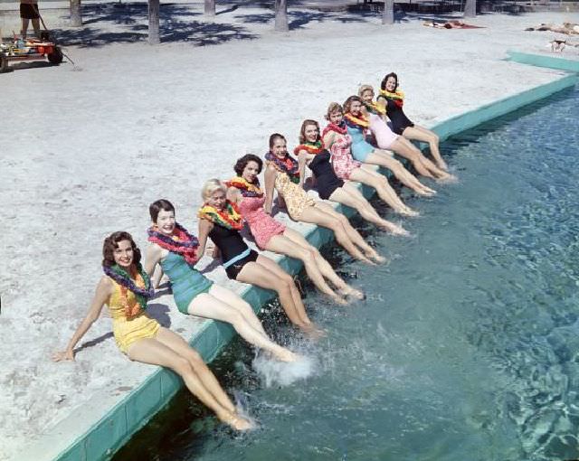 #40 Women wearing leis posing in bathing suits at the beach, circa 1955