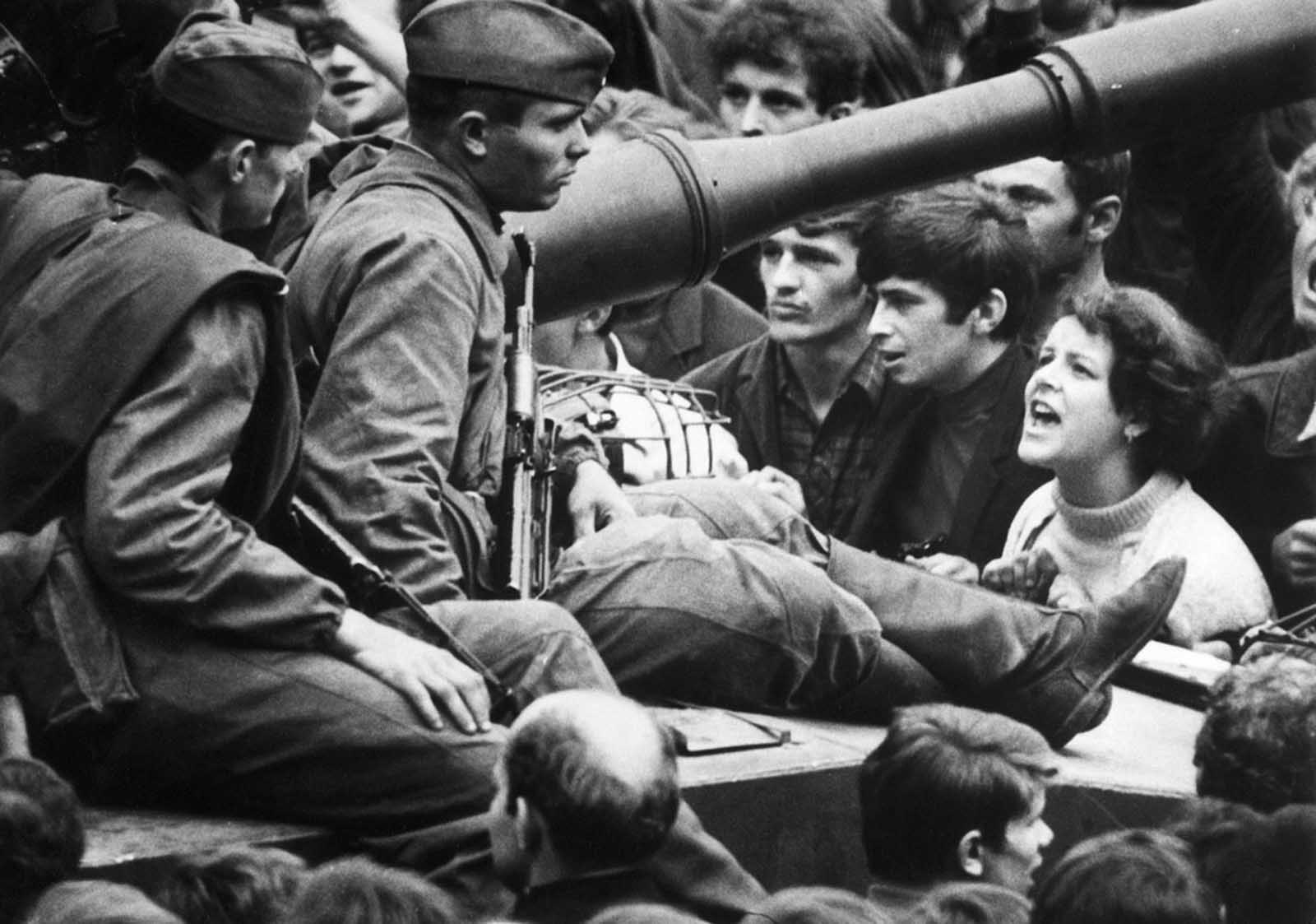 #18 A young Czech lets her feelings be known as she shouts at Soviet soldiers sitting on tanks in the streets of Prague on August 26, 1968.