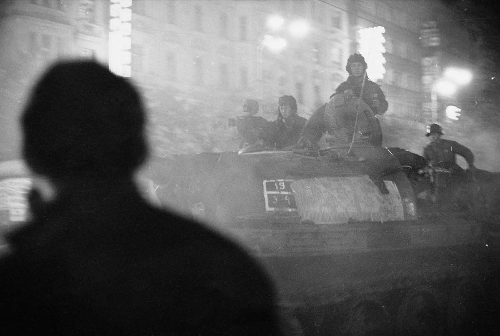 #4 A shadowy figure watches Soviet tanks advance through the streets of Prague after nightfall in August 1968