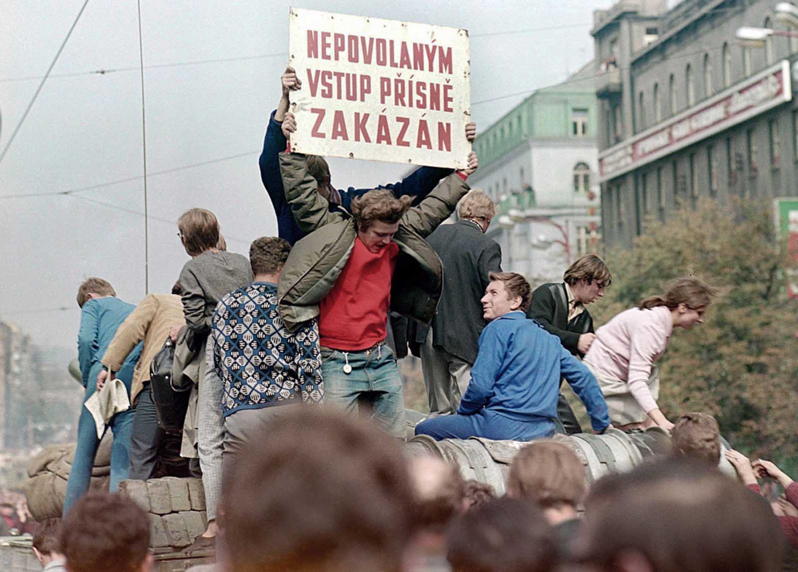 #5 Prague residents ride on top of a Soviet army tank rolling down Wenceslas Square in central Prague