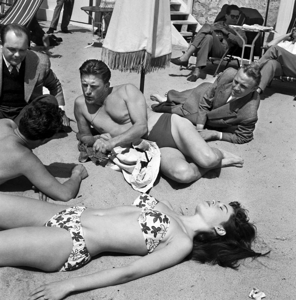#40 Kirk Douglas on the beach at Cannes with a young actress Brigitte Bardot during the 6th International Cannes Film Festival, 1953.