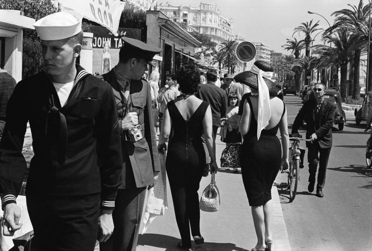 #58 An American serviceman admires passersby on the street in Cannes, 1962.