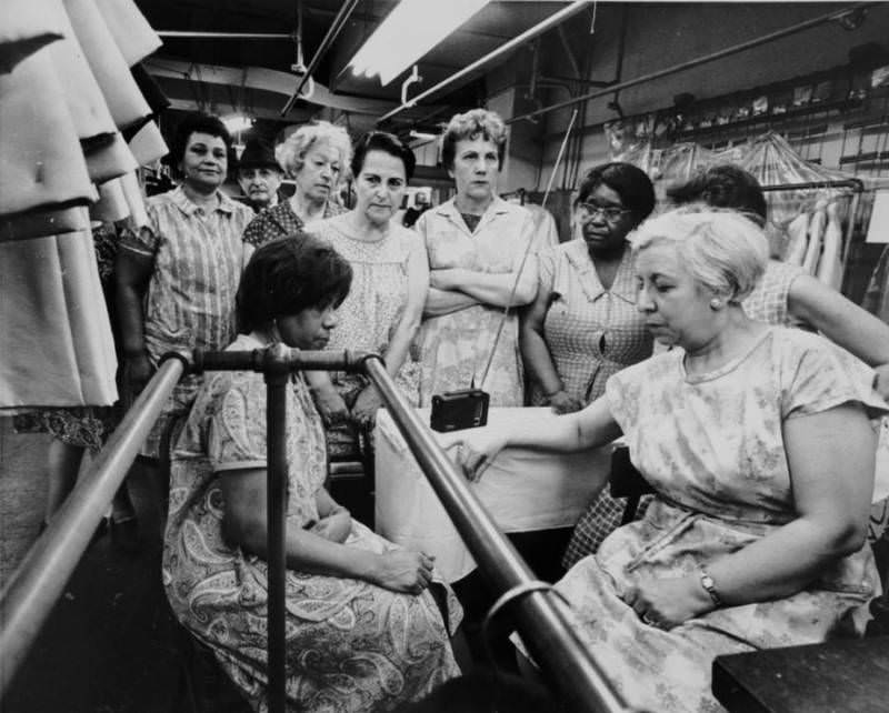 #36 Women at the Abe Schrader clothing shop in New York pause during work to listen to the funeral service for Martin Luther King Jr. on a portable radio. April 8, 1968. Memphis, Tennessee.