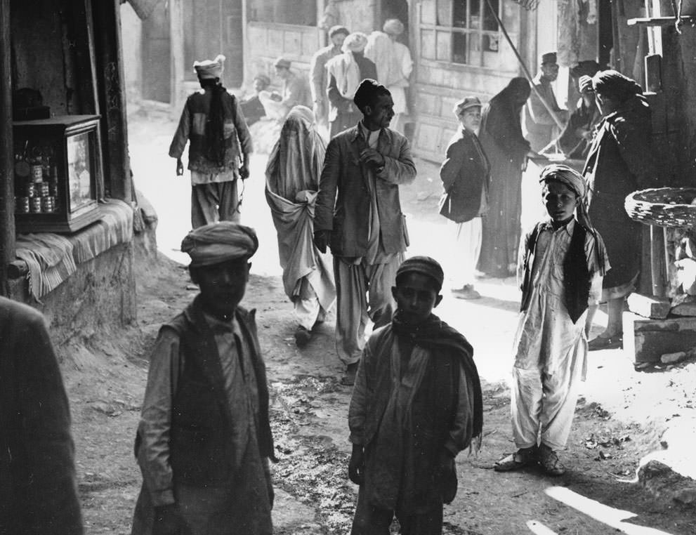 #29 Afghan boys, men, and a woman walk through a street in Kabul, Afghanistan, on March 26, 1954.