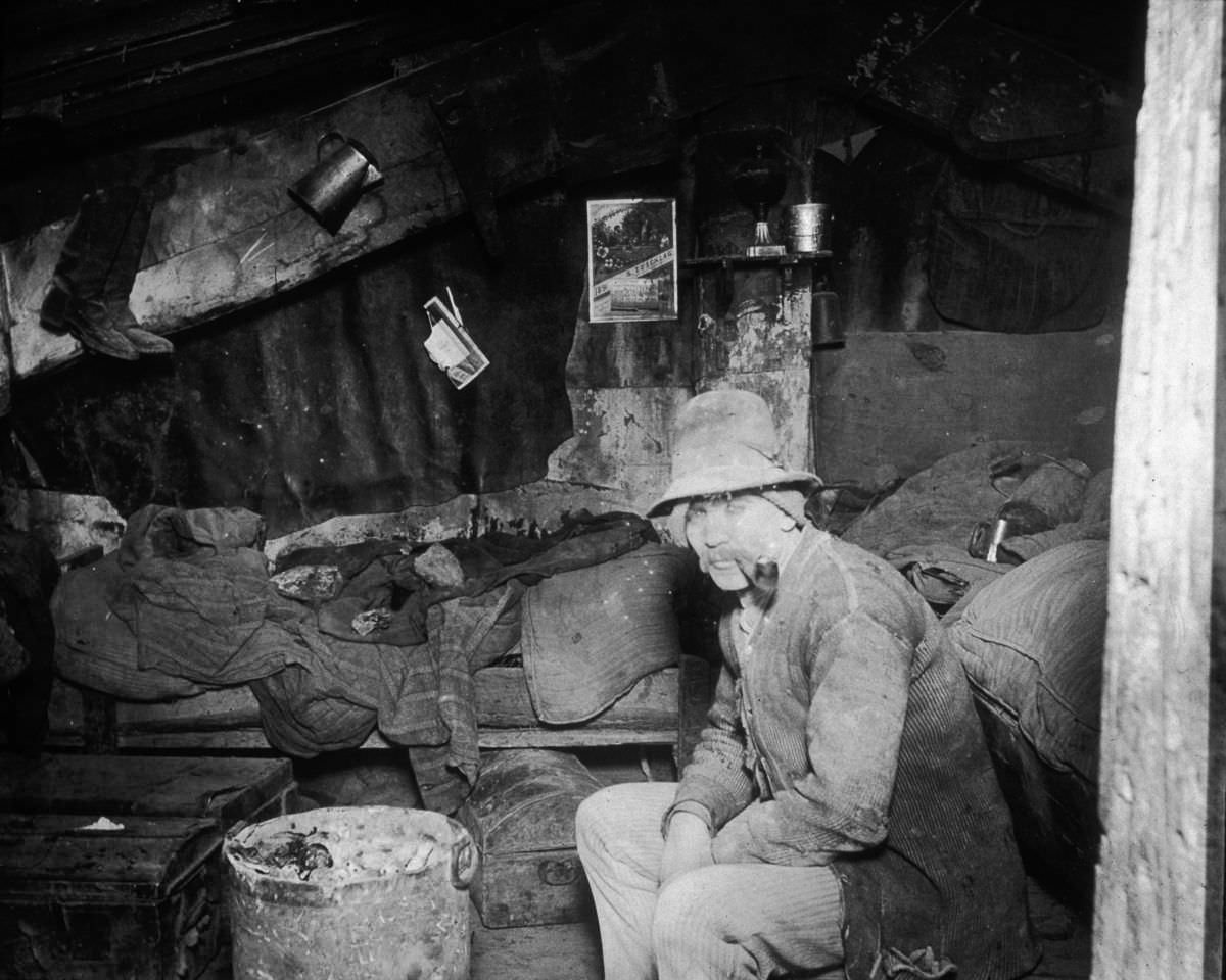 #13 An Italian immigrant man smokes a pipe in his makeshift home under the Rivington Street Dump, 1890