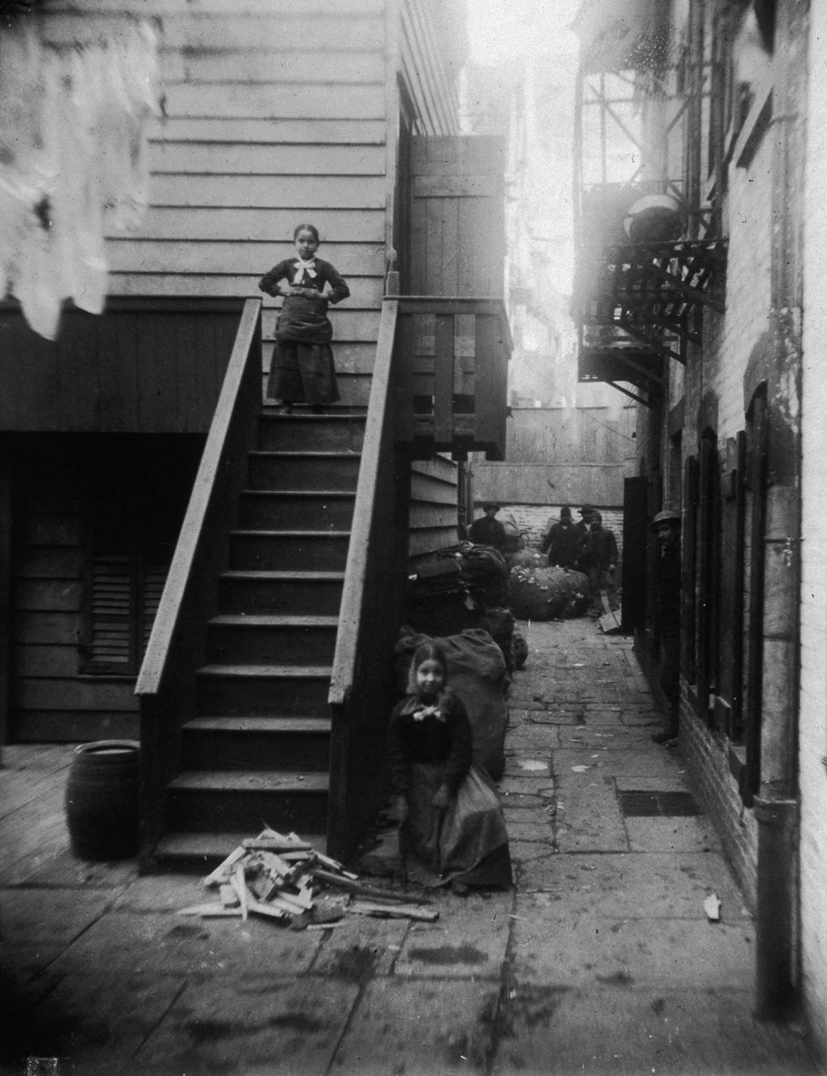 #14 Two young ragpickers stand at a staircase in Baxter Alley, in Little Italy, 1890