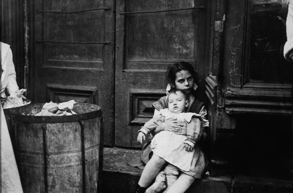 #7 A young girl holds a baby in a doorway, 1890