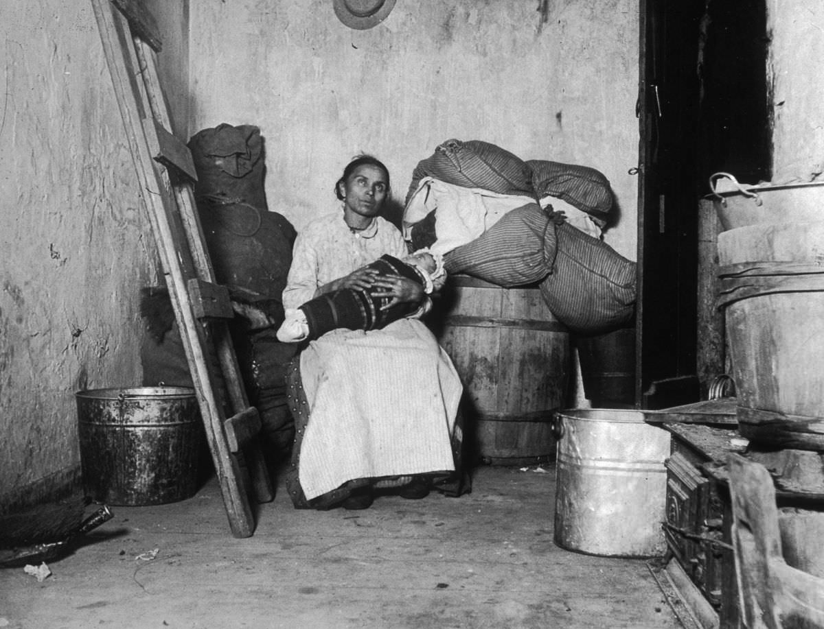 #10 An Italian immigrant rag-picker sits with her baby in a small run-down tenement room on Jersey Street, 1887