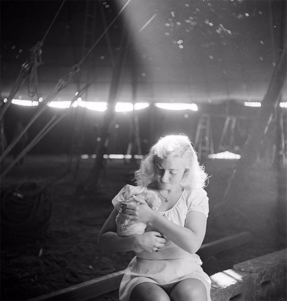 A picture of a circus girl sitting and holding a dog during a rehearsal for the Ringling Bros. and Barnum &; Bailey Circus in Sarasota, FL in 1949.