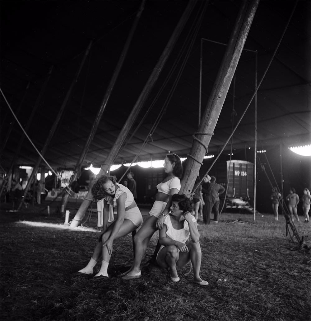 Three circus girls relaxing near a pole during a rehearsal for the Ringling Bros. and Barnum &; Bailey Circus in Sarasota, FL in 1949.