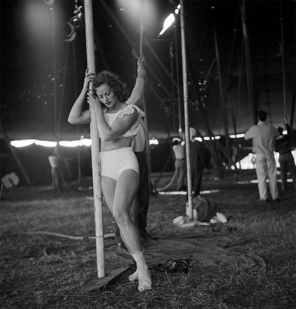 A circus girl standing near a pole while an unidentified man is holding a rope during a rehearsal for the Ringling Bros. and Barnum &; Bailey Circus in Sarasota, FL in 1949.