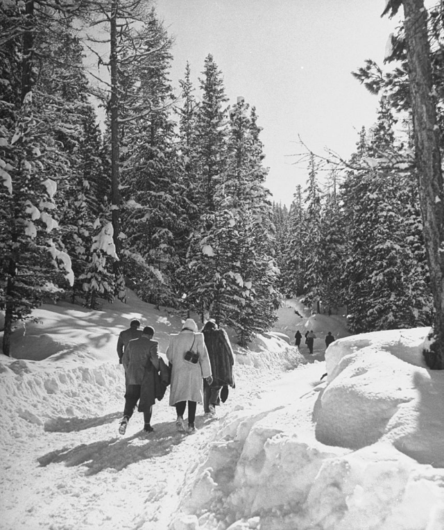 #28 People walking from town to jumping hill in snow-covered ski-resort village.