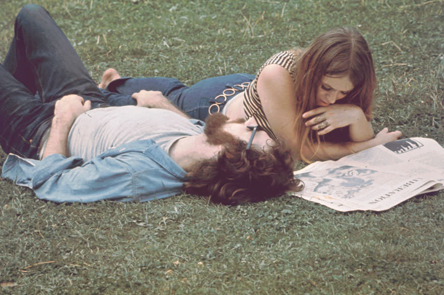 #51 A Young Woman Lies On Grass And Reads Newspaper, A Young Man Beside Her, During The Woodstock Music And Arts Fair