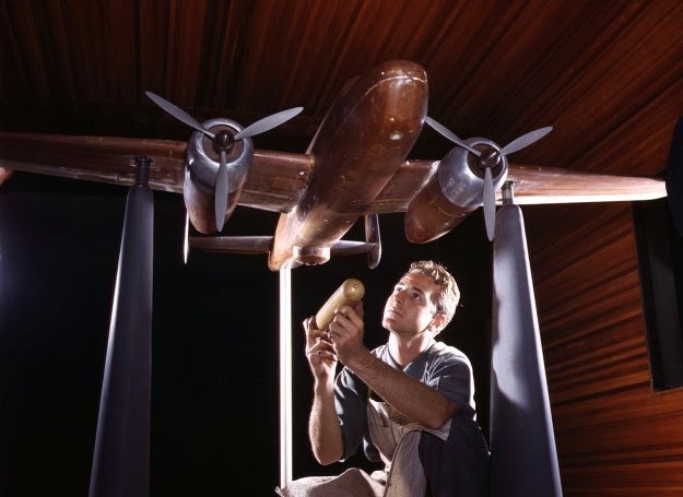 #159 An experimental scale model of the B-25 plane is prepared for wind tunnel tests in the plant of the North American Aviation, Inc., Inglewood, California. The model maker holds an exact miniature reproduction of the type of bomb the plane will carry. October, 1942