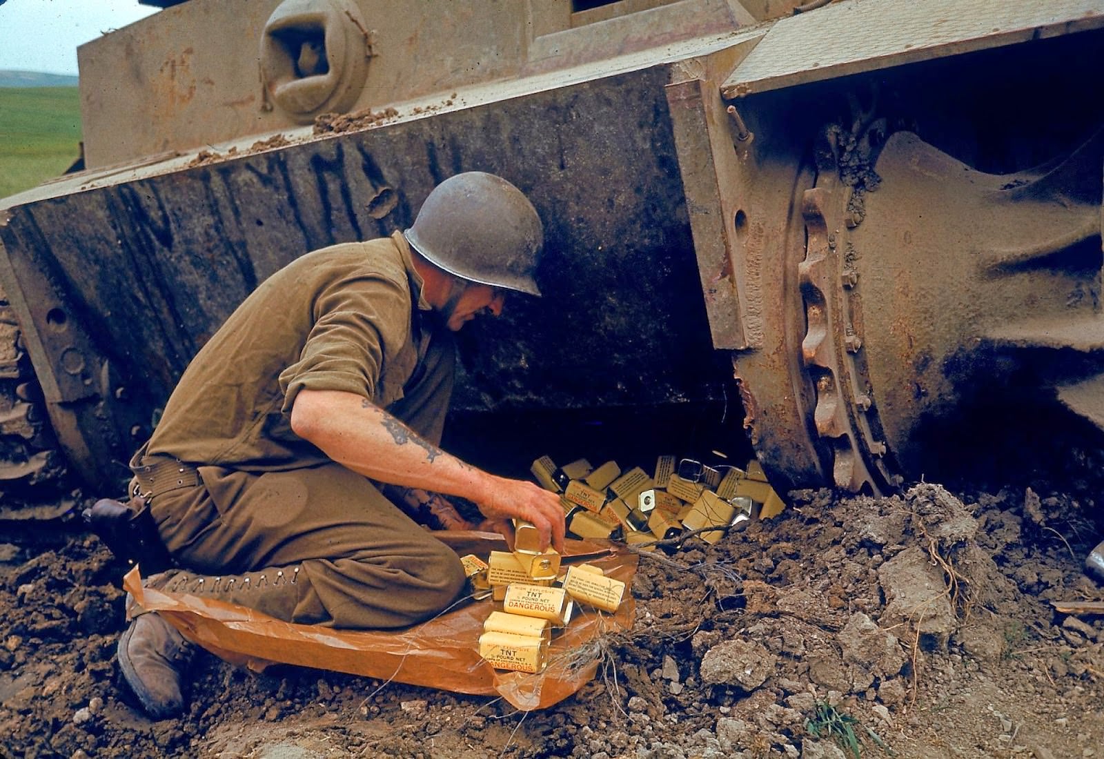 #13 A US Army Corps of Engineers solider packs 1/2 pound tins of the explosive TNT under one end of an abandoned German tank in preparation for detonation during military operations in the El Guettar Valley, Tunisia, early 1943.