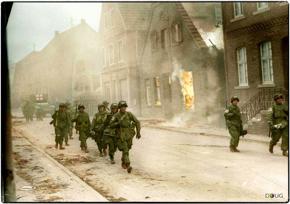 #75 Troops of the 17th U.S. Airborne Division, First Allied Airborne Army, march past a blazing building in Appelhülsen, Germany, as they advance toward the city of Münster, nine miles to the northeast.