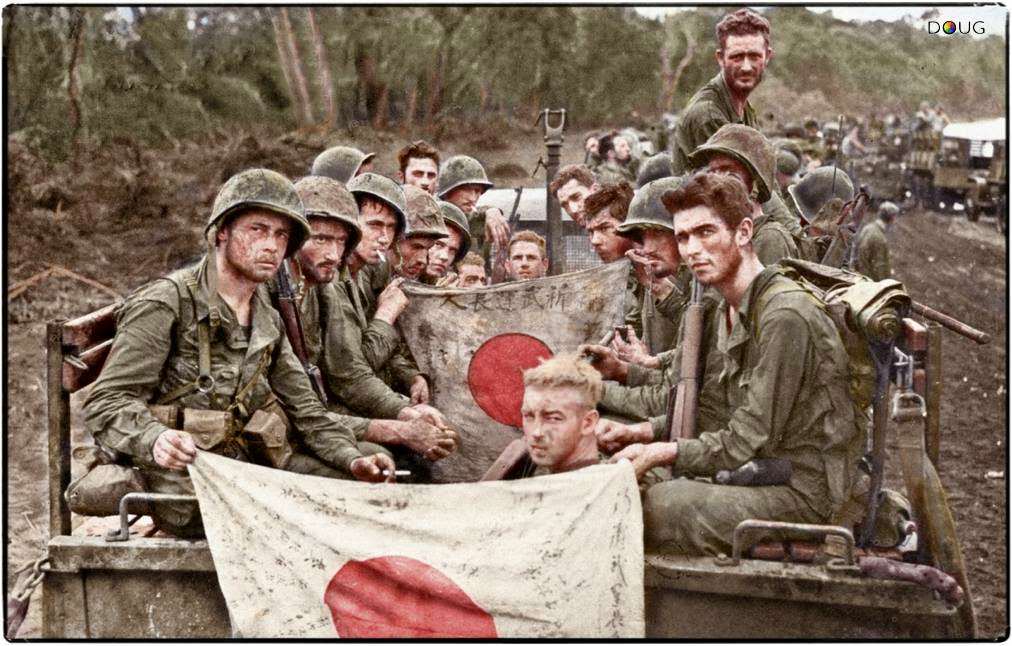 #29 The strain and fatigue of 23 days on the line is shown by Marines of Combat Team ‘C’, 2/7th US Marines, 1st Marine Division seen here displaying Japanese battle flags captured during the Battle of Cape Gloucester. 14-15th January 1944