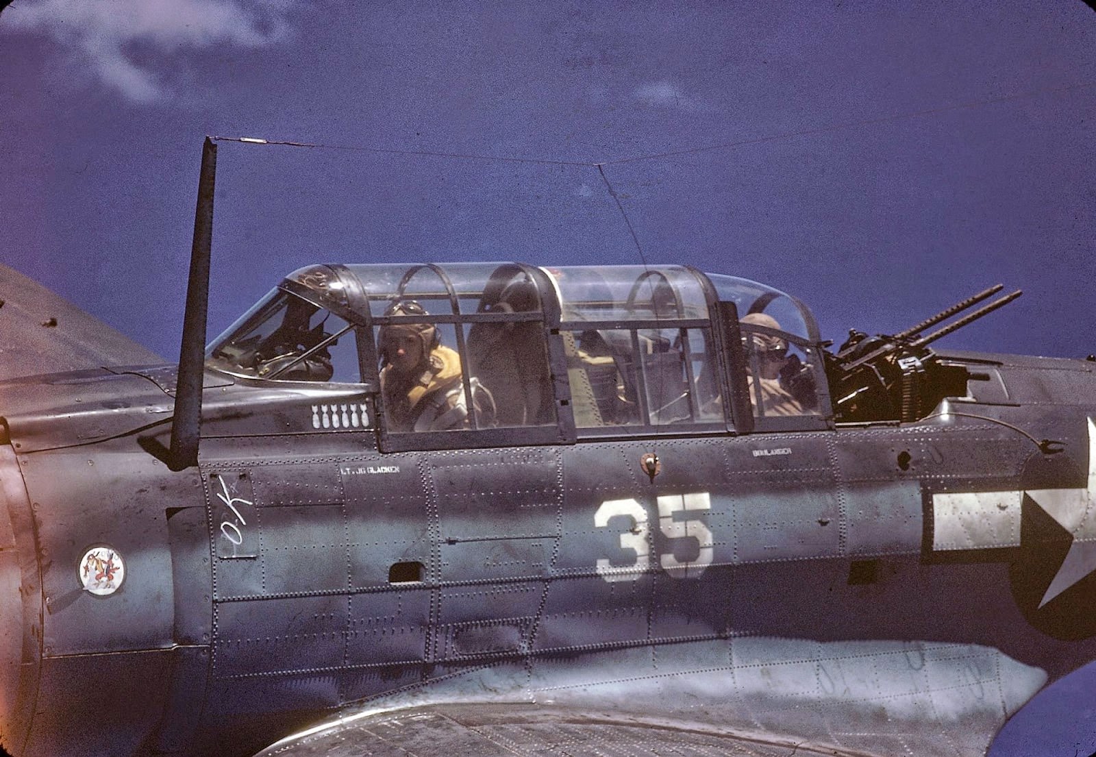 #9 Close-up, in-flight view of a Douglas SBD Dauntless piloted by American Lt. George Glacken (left) with his gunner Leo Boulanger, near New Guinea, early April, 1944.