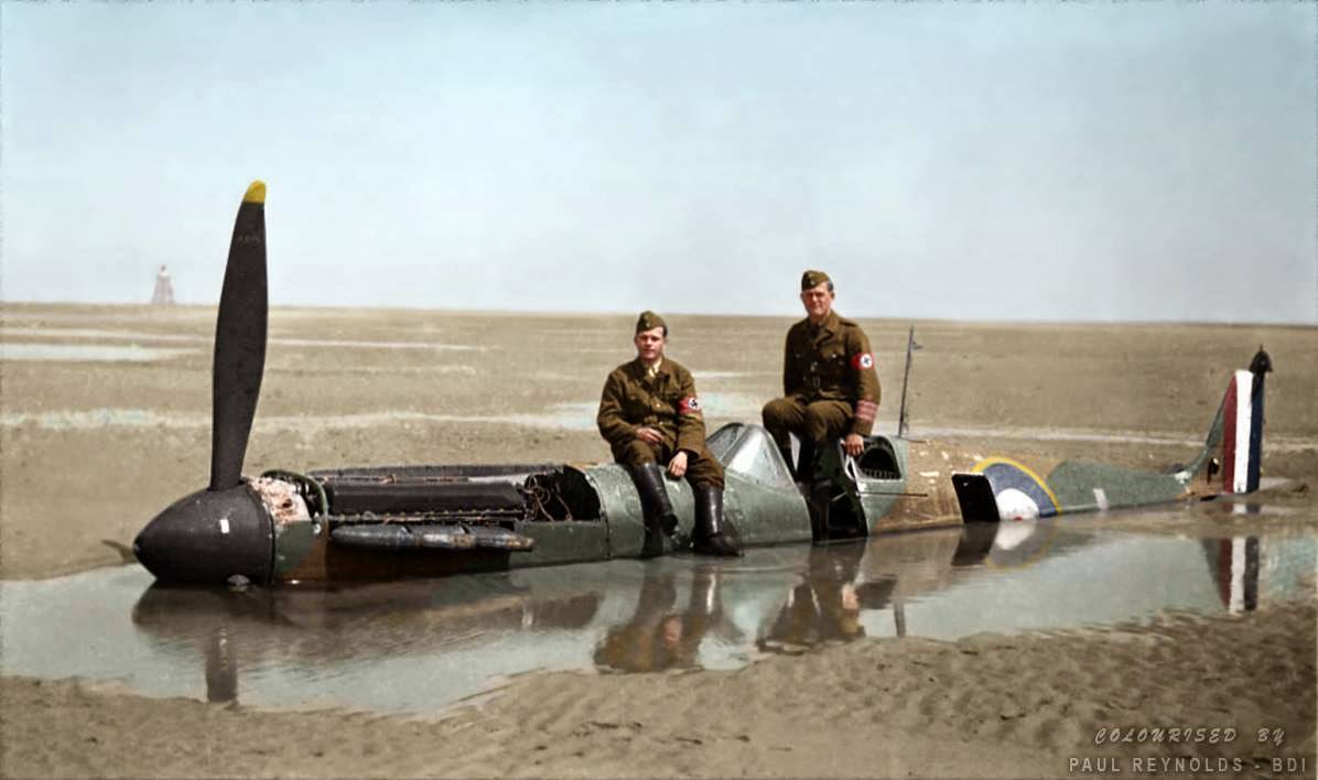 #96 Two German members of the Organisation Todt (involved in the construction of the Atlantic Wall) are sitting on the Spitfire brought down on the wet sands at Calais by Flying Officer Peter Cazenove.
