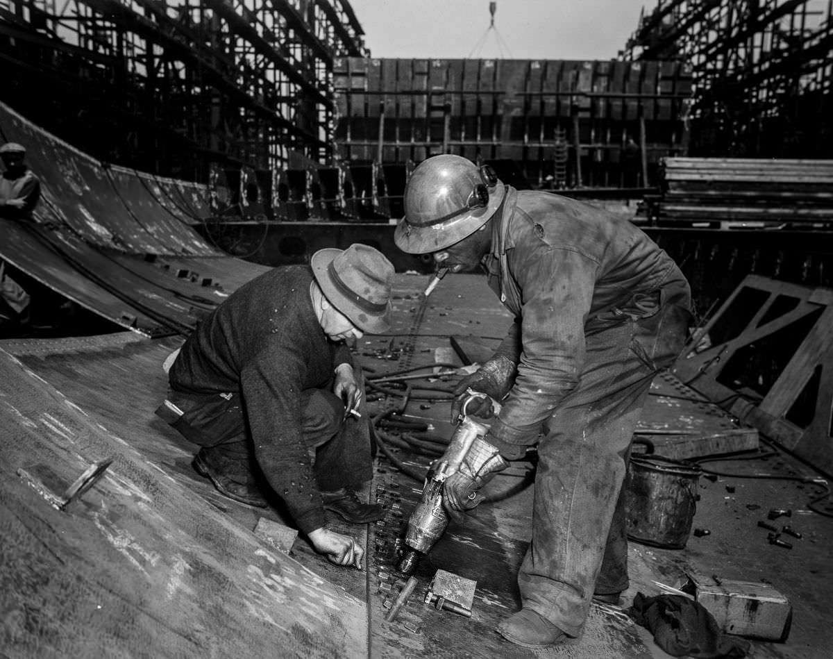 #28 Workers tighten bolts with a pneumatic wrench in the belly of the Frederick Douglass