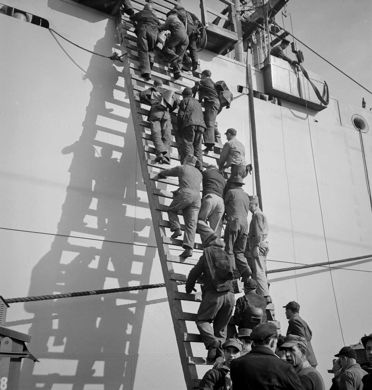 #7 Workers climb a ladder on the outfitting pier
