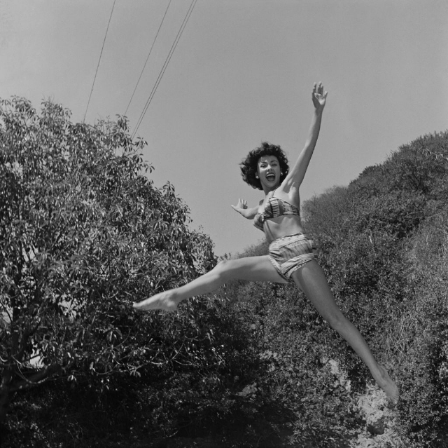 #6 Rita Moreno in a studio session sitting with her legs crossed looking directly at the camera, Hollywood, 1954.