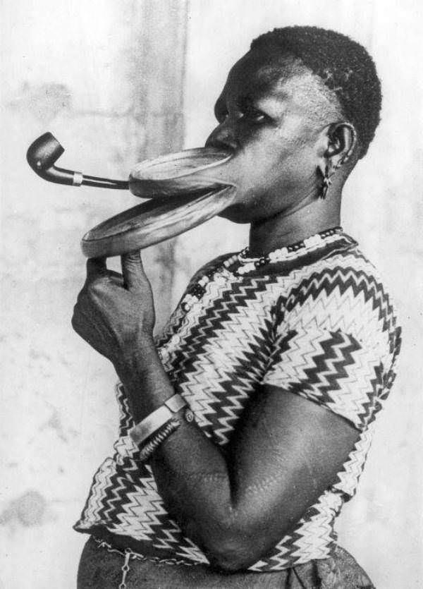 Madam Gustika, who was billed as being from the “Duckbill tribe,” is seen here smoking a pipe through the large plates in her lip, 1930