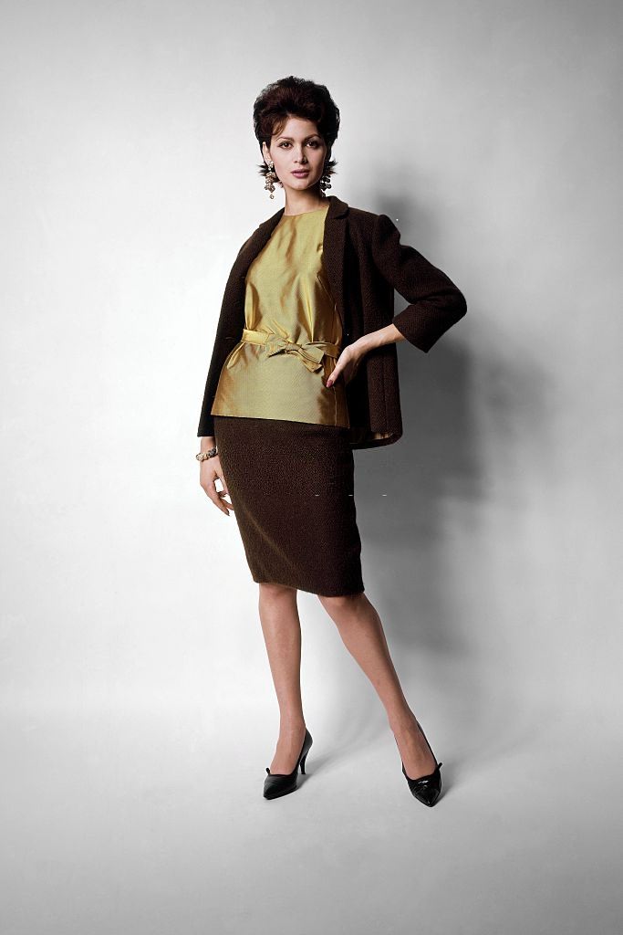 #12 Model wearing green-tea wool suit with lemon colored silk twill overblouse, tied at the waist, Vogue 1961