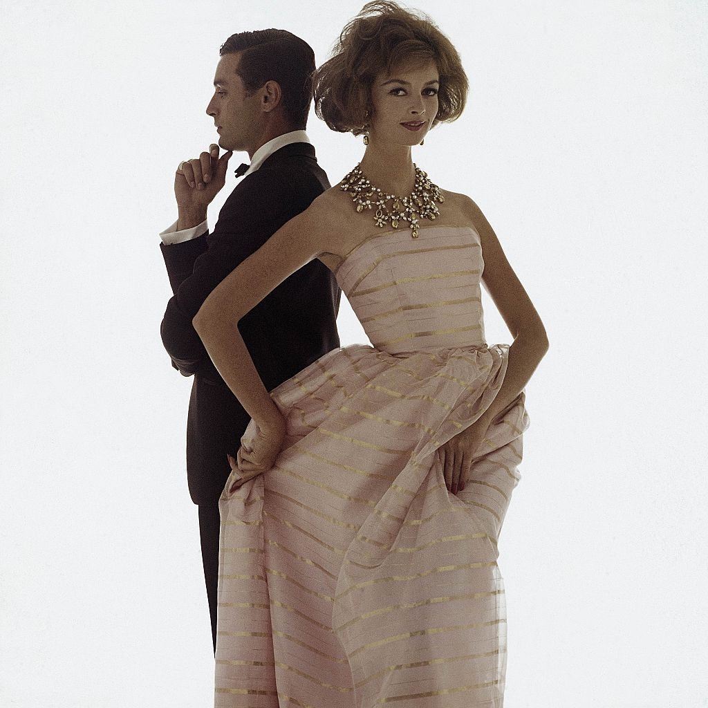 #13 Fashion model in a ball gown of pink organza and gold lurex-striped with matching stole, Glamour 1961