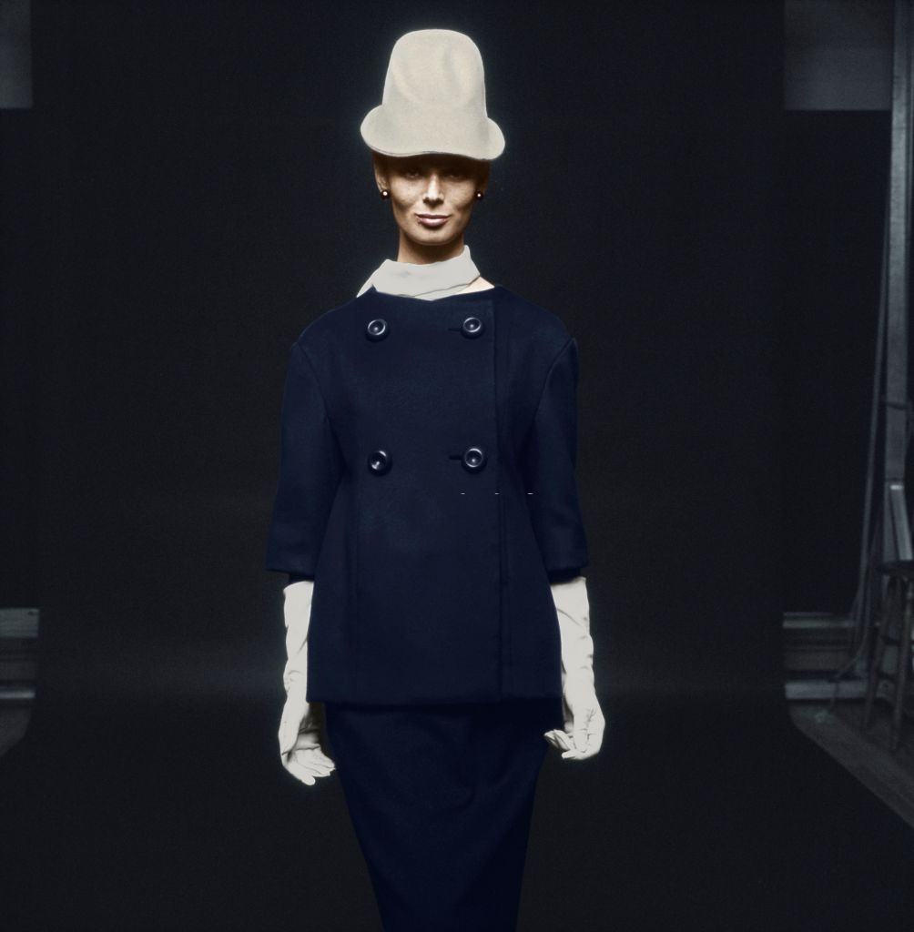 #21 Fashion model wearing wool suede cloth suit in indigo blue, with white silk crepe scarf, white gloves and white felt fedora, Vogue 1963