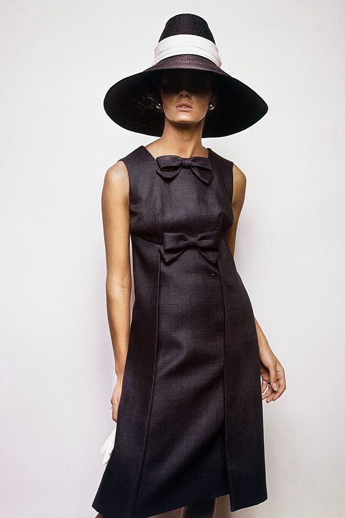 #22 Model wearing navy blue, sleeveless dress, Vogue 1963