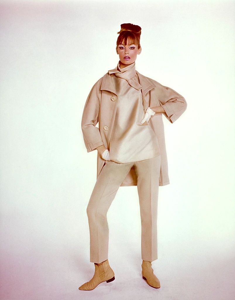 #36 Model Jean Shrimpton wearing trouser ensemble in shades of beige, with coat, trousers, and tie neck top, Vogue 1964