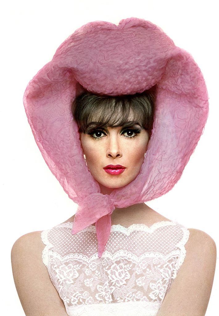 #37 Model Wilhelmina with pink Lilly Dache scarf around head and white lace dress, Vogue 1964
