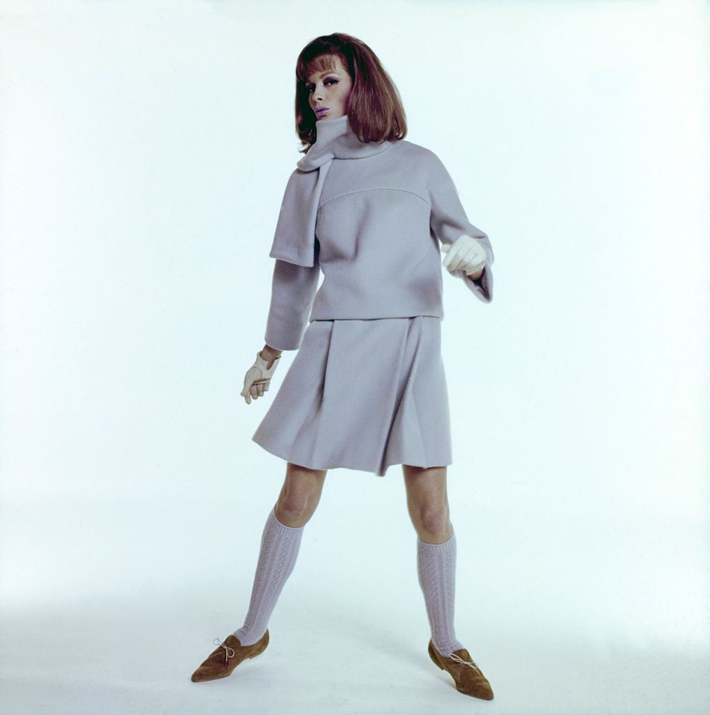 #40 Model wearing lite blue two piece skirt ensemble with cowl neck and pleated skirt, Vogue 1964