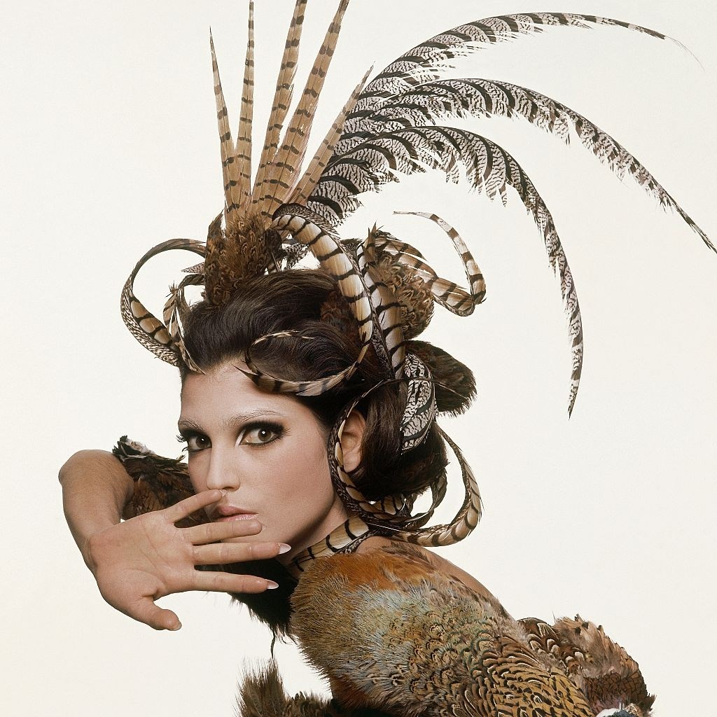#43 Fashion model from series of beauty shots based on the four seasons, here for autumn 1965, with elaborate feather headdress, covered up eyebrows, and heavy lashes, Vogue 1965