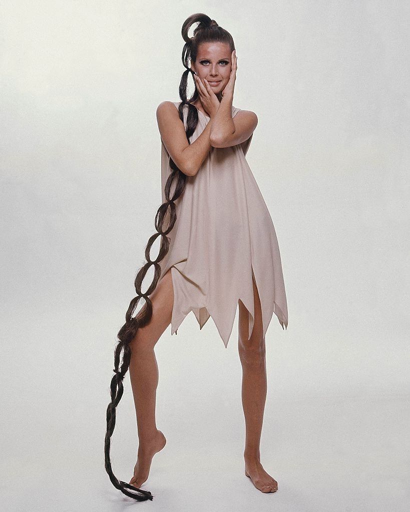 #64 Model sporting floor-length hairpiece wearing sleeveless jagged-hem dress, Vogue 1966