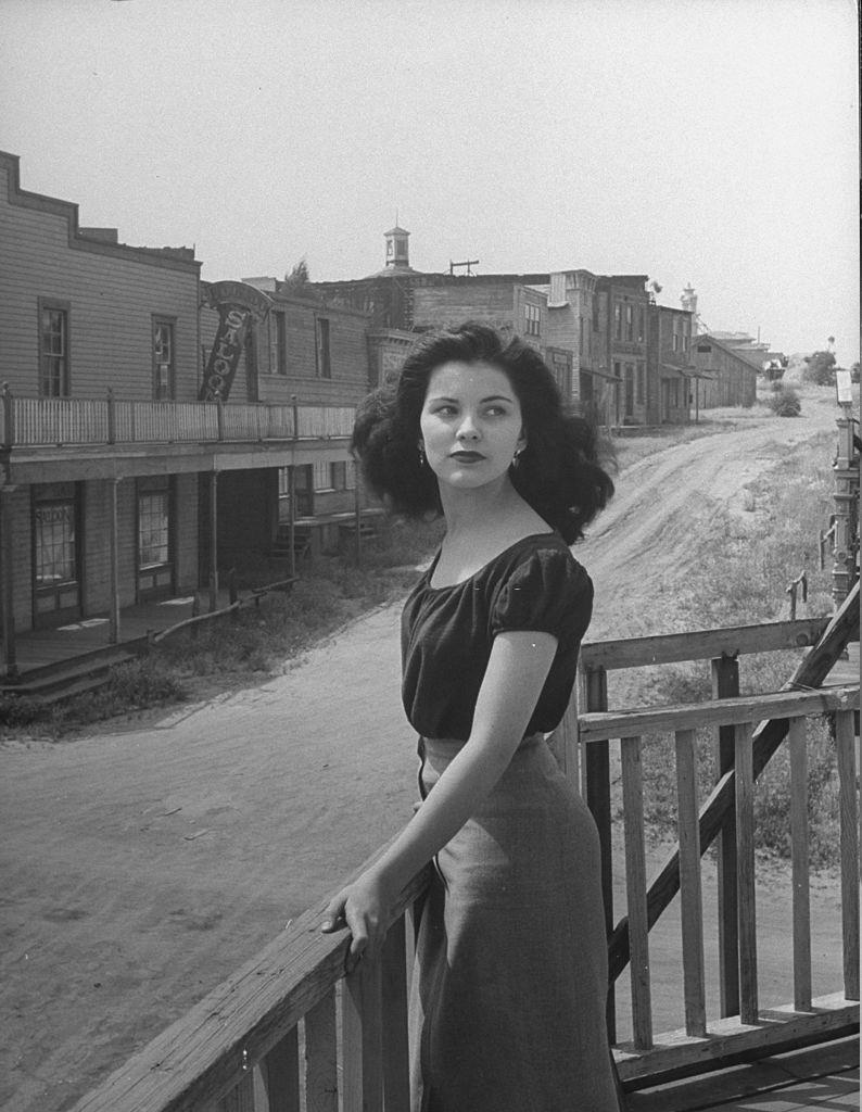 #37 Debra Paget, standing on a balcony in the middle of the desolate town.